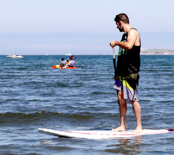 chico practicando paddle surf en la playa