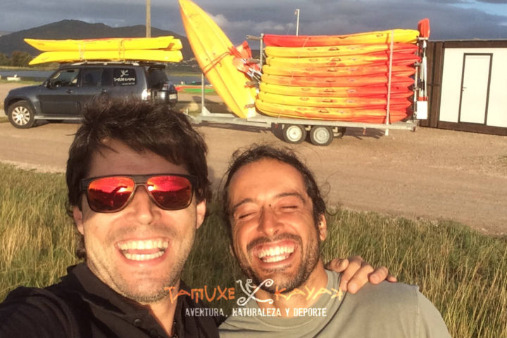 Amigos sonriendo delante de unos kayaks